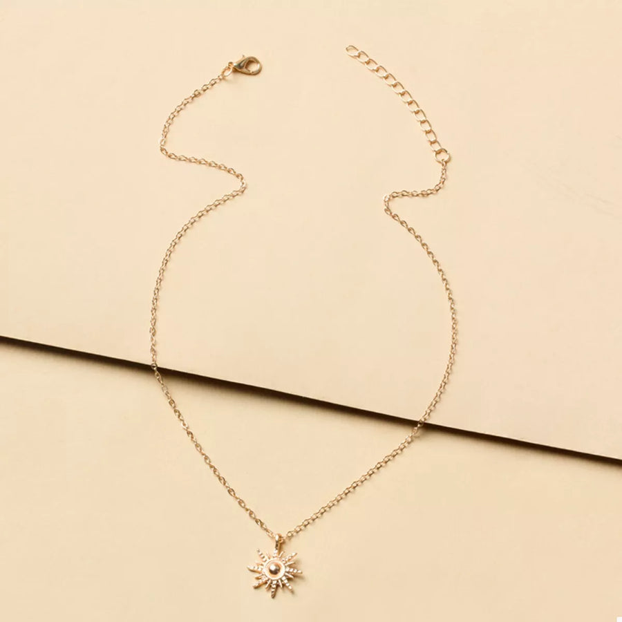 Gold sunburst pendant necklace with delicate chain and lace trim detail.