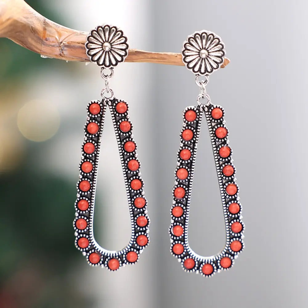 Coral bead teardrop earrings with silver flower tops.