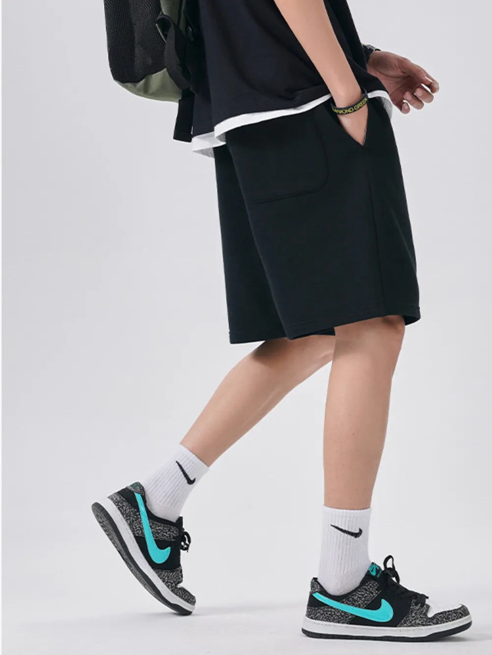 Black chino shorts with drawstring waist and relaxed fit, styled with white socks and sneakers.