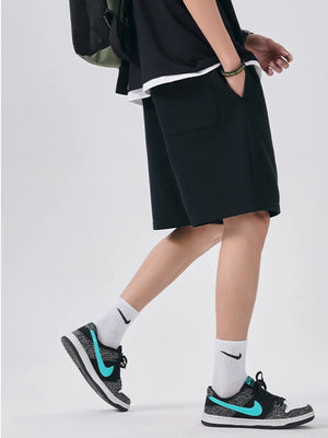 Black chino shorts with drawstring waist and relaxed fit, styled with white socks and sneakers.