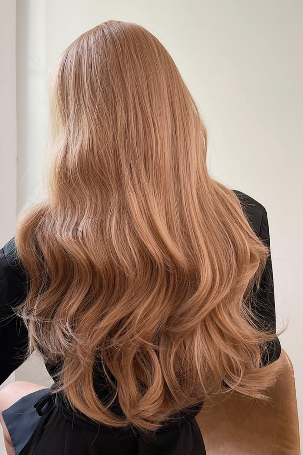 Strawberry blonde wig with long, loose waves and baguette bangs.