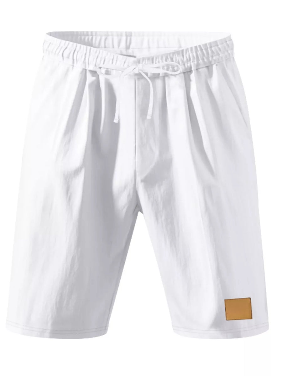 White chino shorts with drawstring waist and faux leather patch detail.