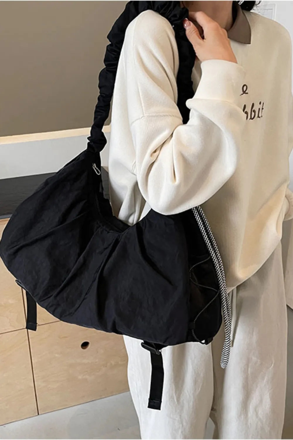 Black gathered crescent shoulder bag with ruched strap and drawstring detail