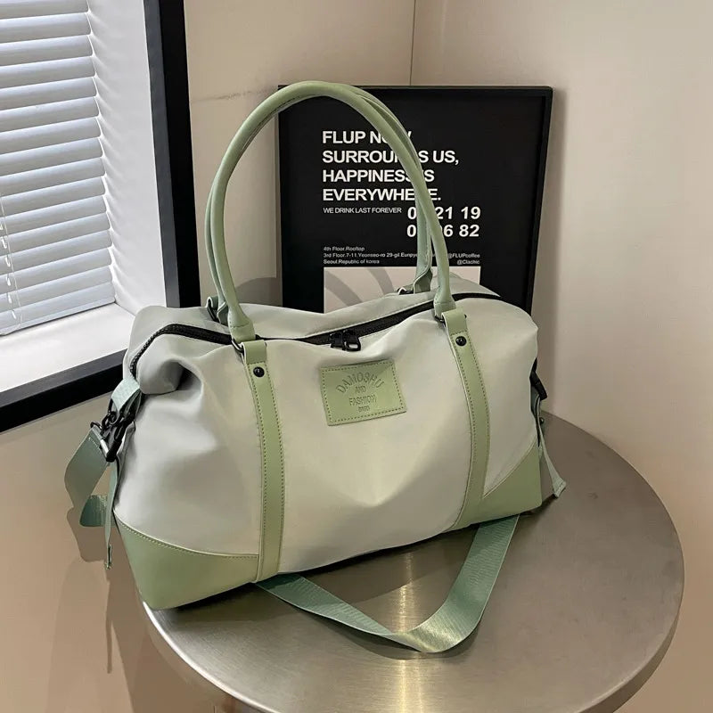 Duffle-Sling bag in light gray with sage green accents and strap, featuring a patch logo.