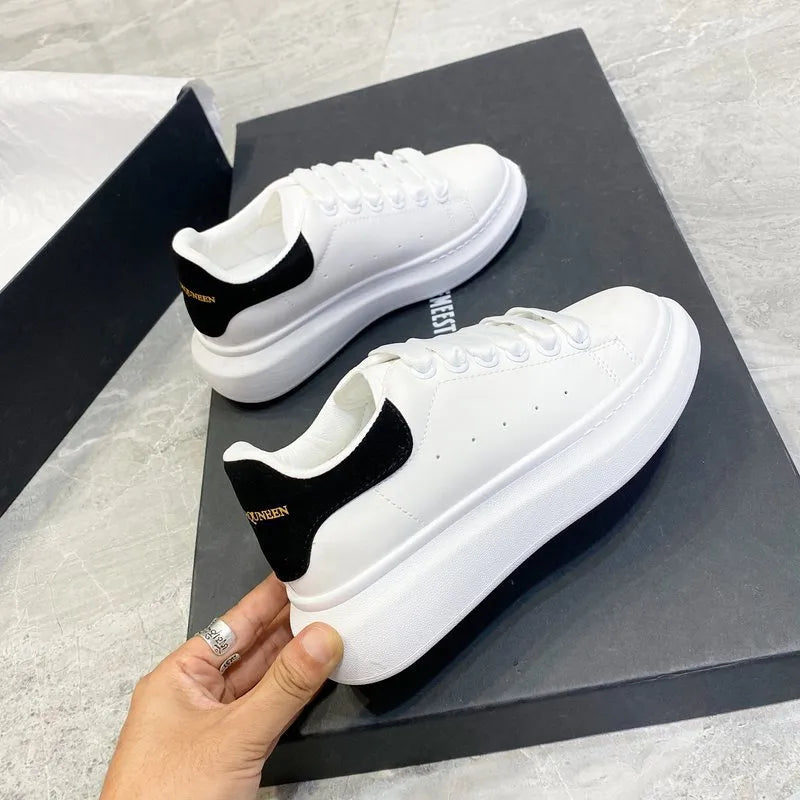 White platform sneakers with black suede heel detail and gold lettering