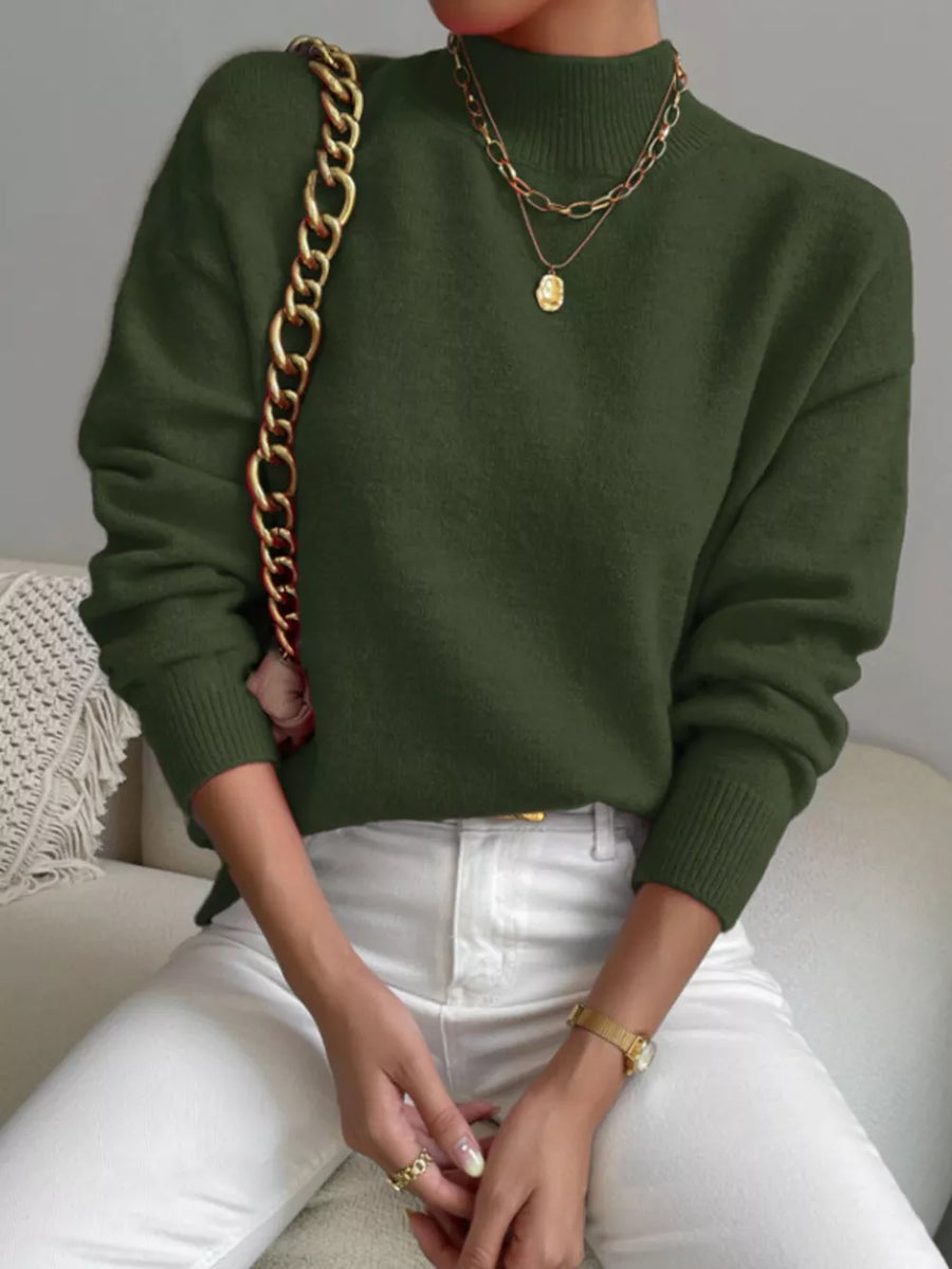 Army green mock neck sweater with dropped shoulders, paired with white jeans.