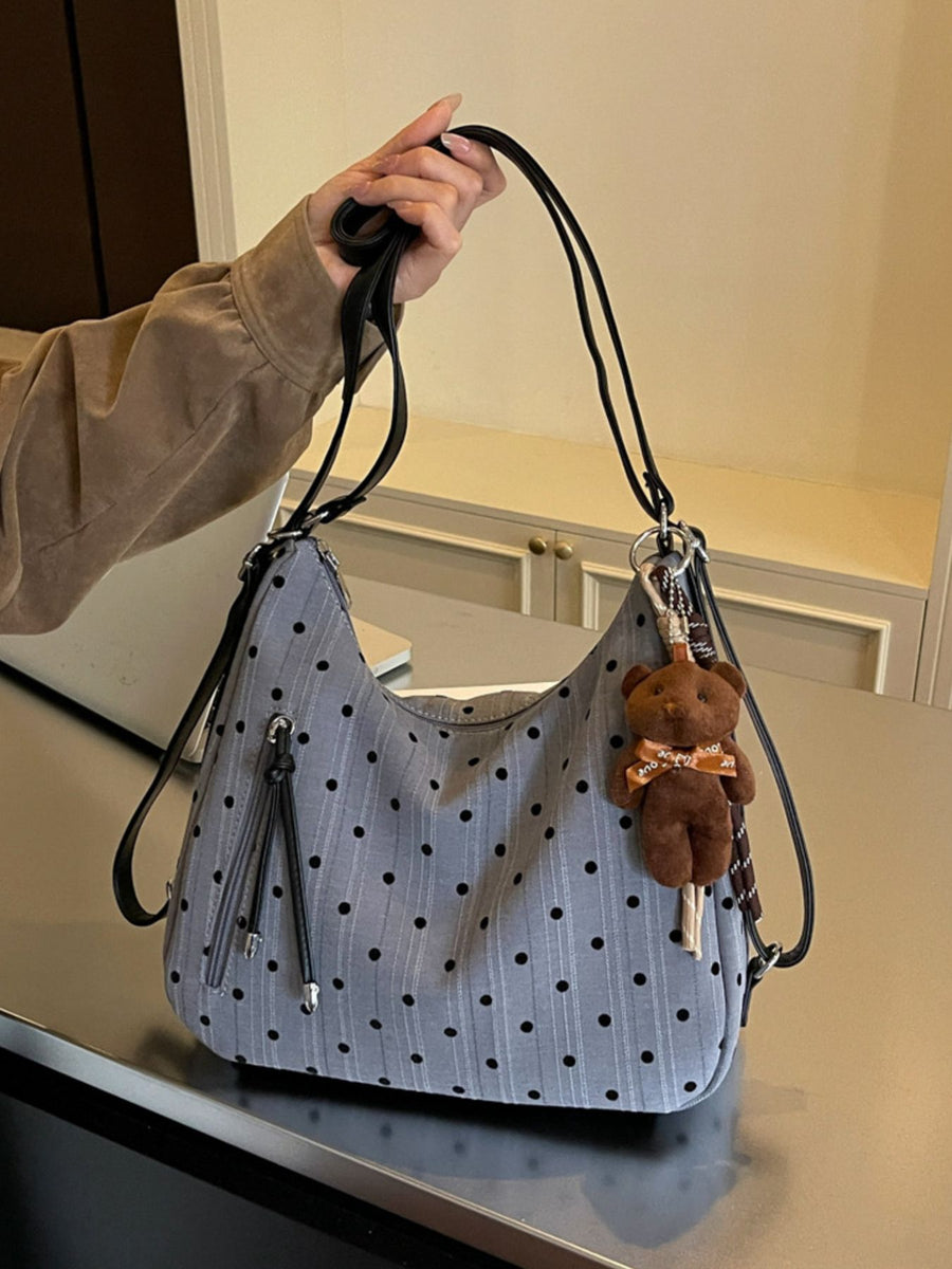 black shoulder bag featuring exterior zip pocket and polka dot