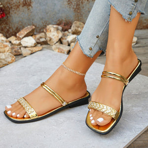 Gold flat sandals with rhinestone embellished straps and double band detail.