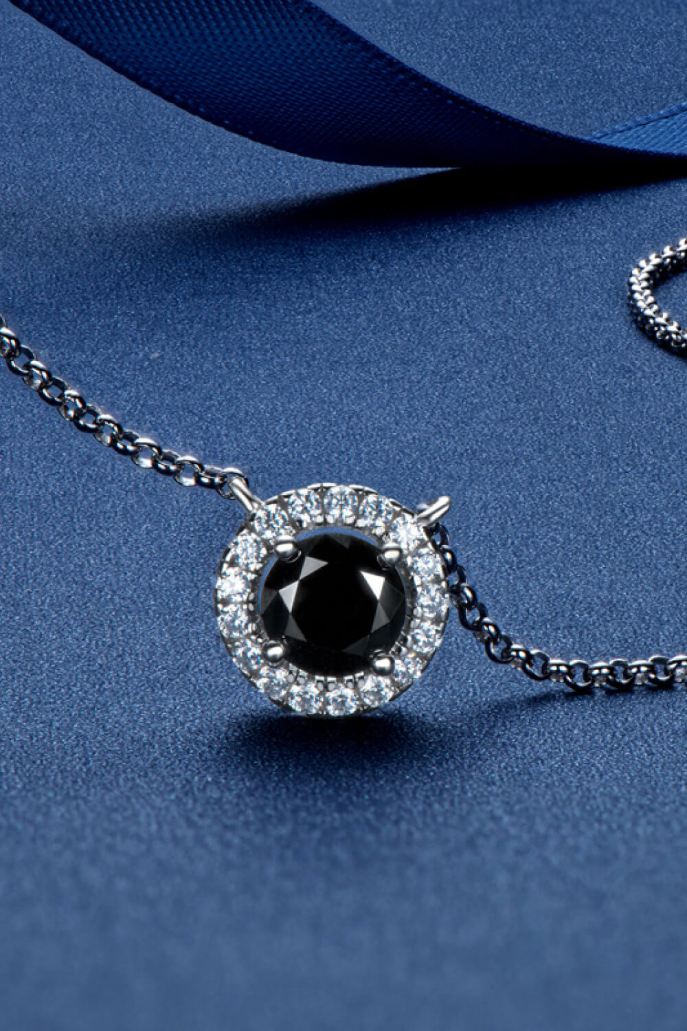 Black halo moissanite necklace with a round black center stone and clear accent stones on a silver chain.