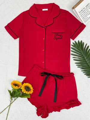 Red pajama set with black trim and "Sleep Squad" embroidery