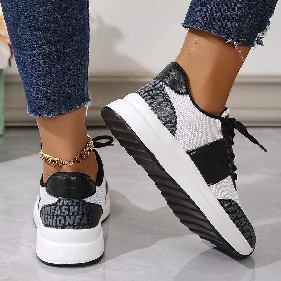 White and black lace-up sneakers with mesh detailing and text print accents.