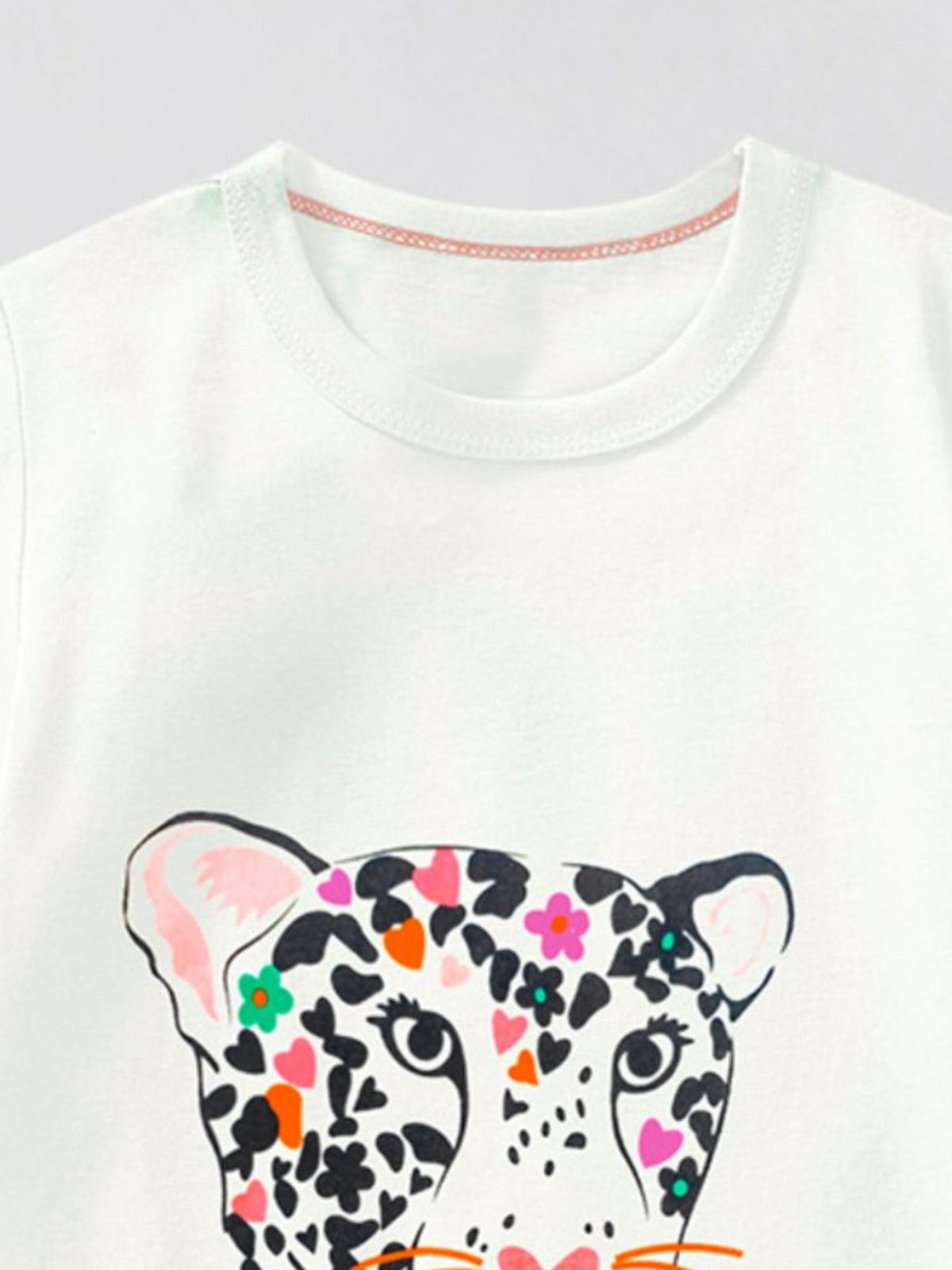 White cotton t-shirt with a colorful leopard graphic and floral accents.