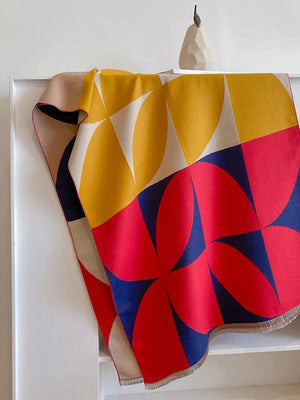 Geometric patterned soft scarf in yellow, red, blue, and beige with fringes.