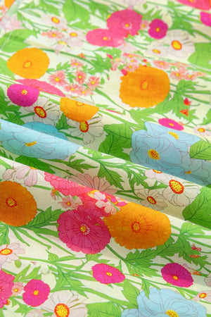 Vibrant floral maxi dress fabric with ruffled neckline detail, featuring orange, pink, blue, and white flowers on a light