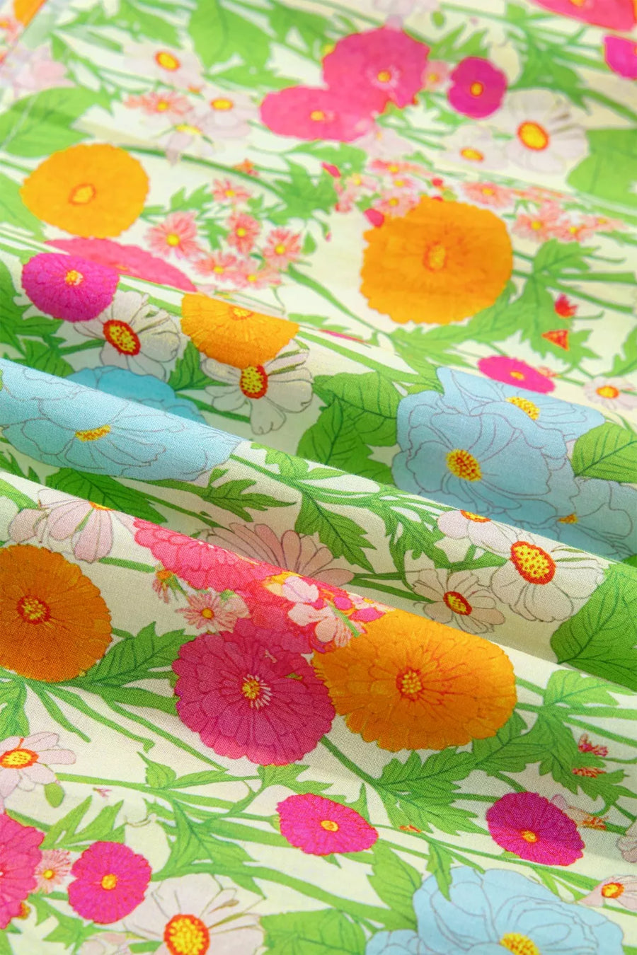 Vibrant floral maxi dress fabric with ruffled neckline detail, featuring orange, pink, blue, and white flowers on a light