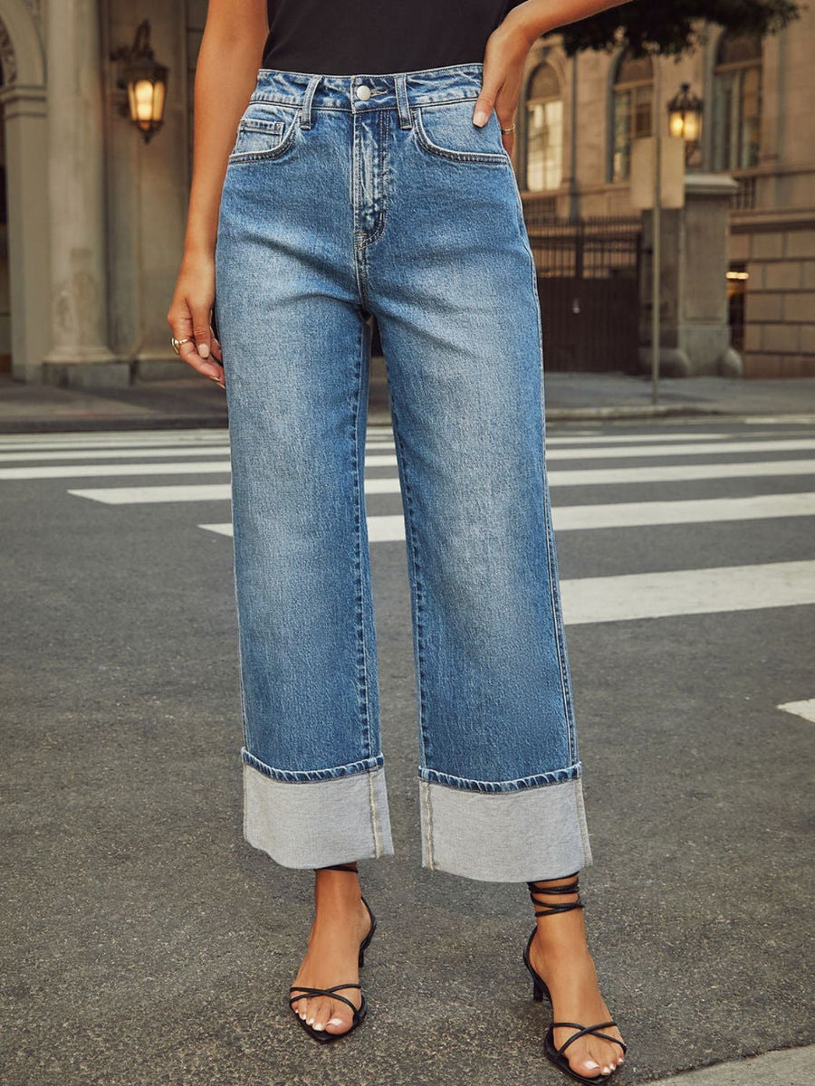 Light wash denim jeans with wide legs and cuffed hems.