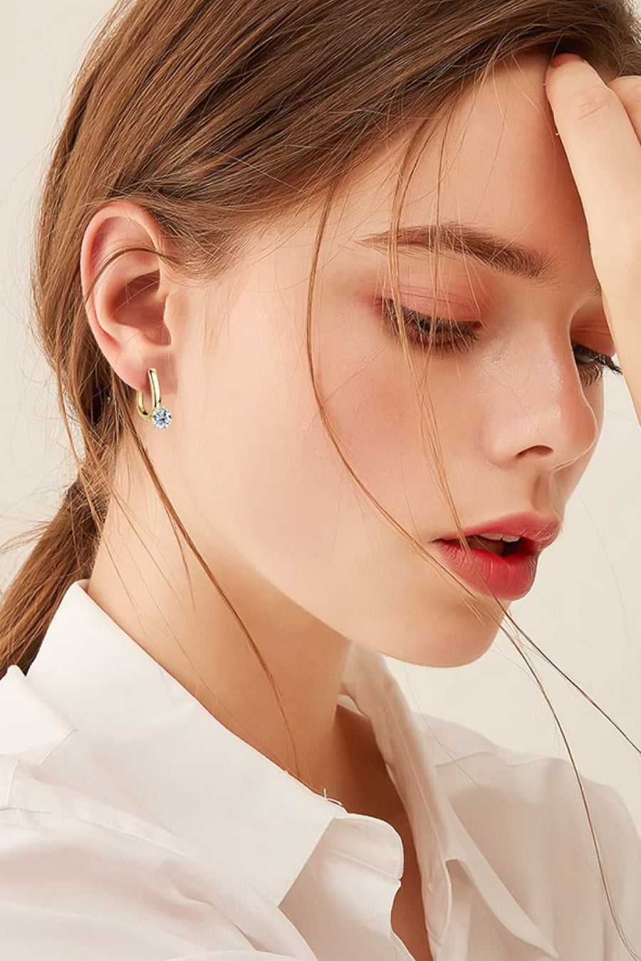 Gold solitaire huggie hoop earrings with a single clear stone detail.