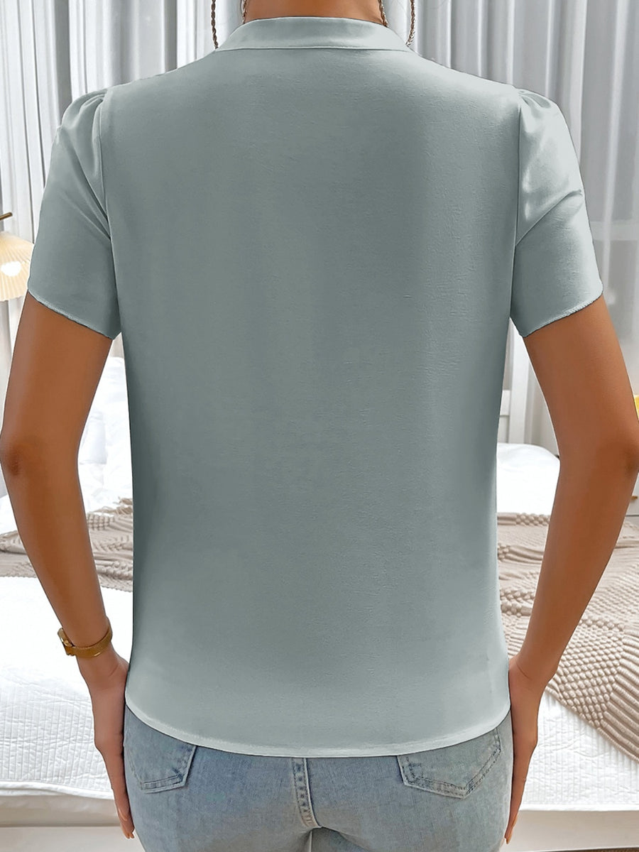 Light blue blouse with notched neckline and petal sleeves, buttoned back detail.