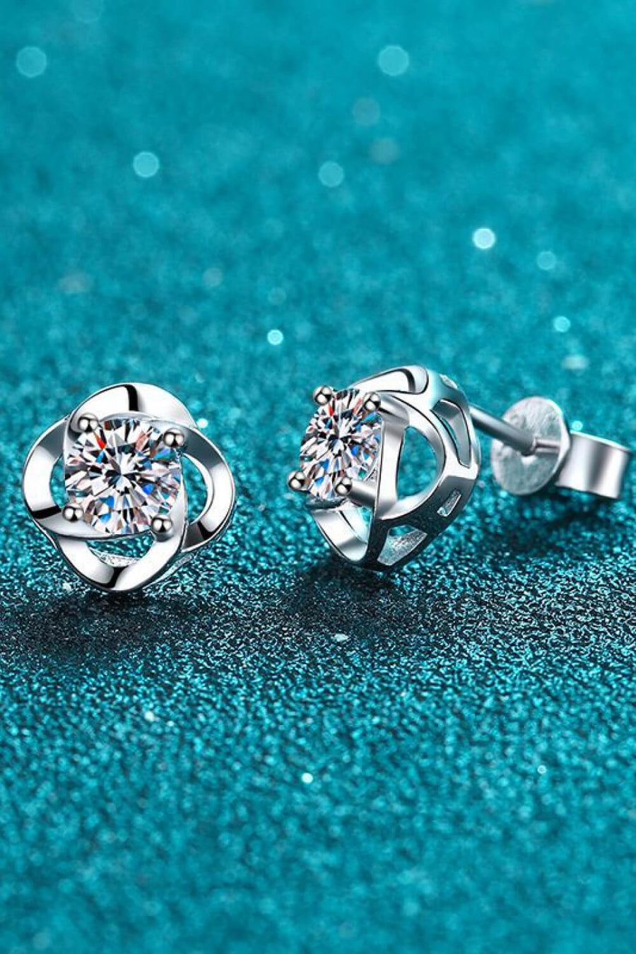 Silver four-leaf clover stud earrings with a central sparkling stone.