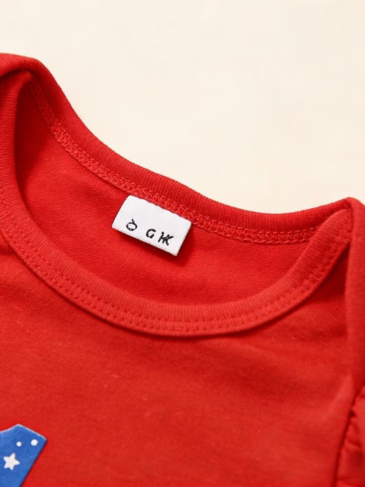 Red baby onesie with a white tag and a blue star detail.