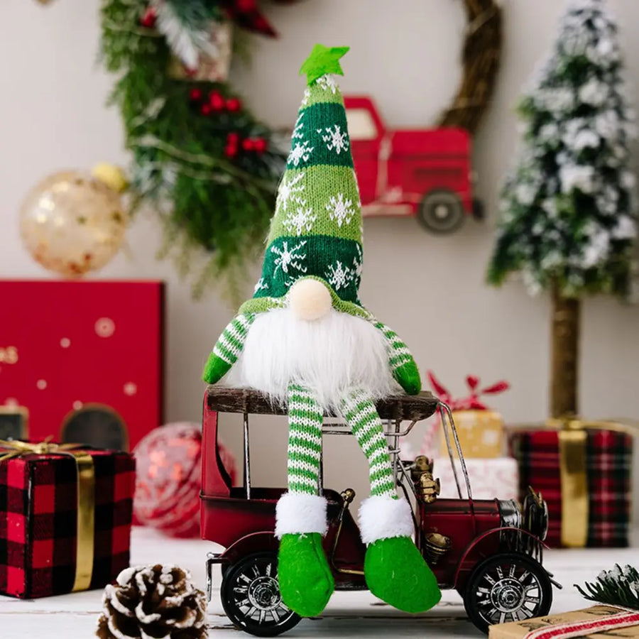 Illuminated knit gnome in green with snowflake pattern, sitting on a red toy car.