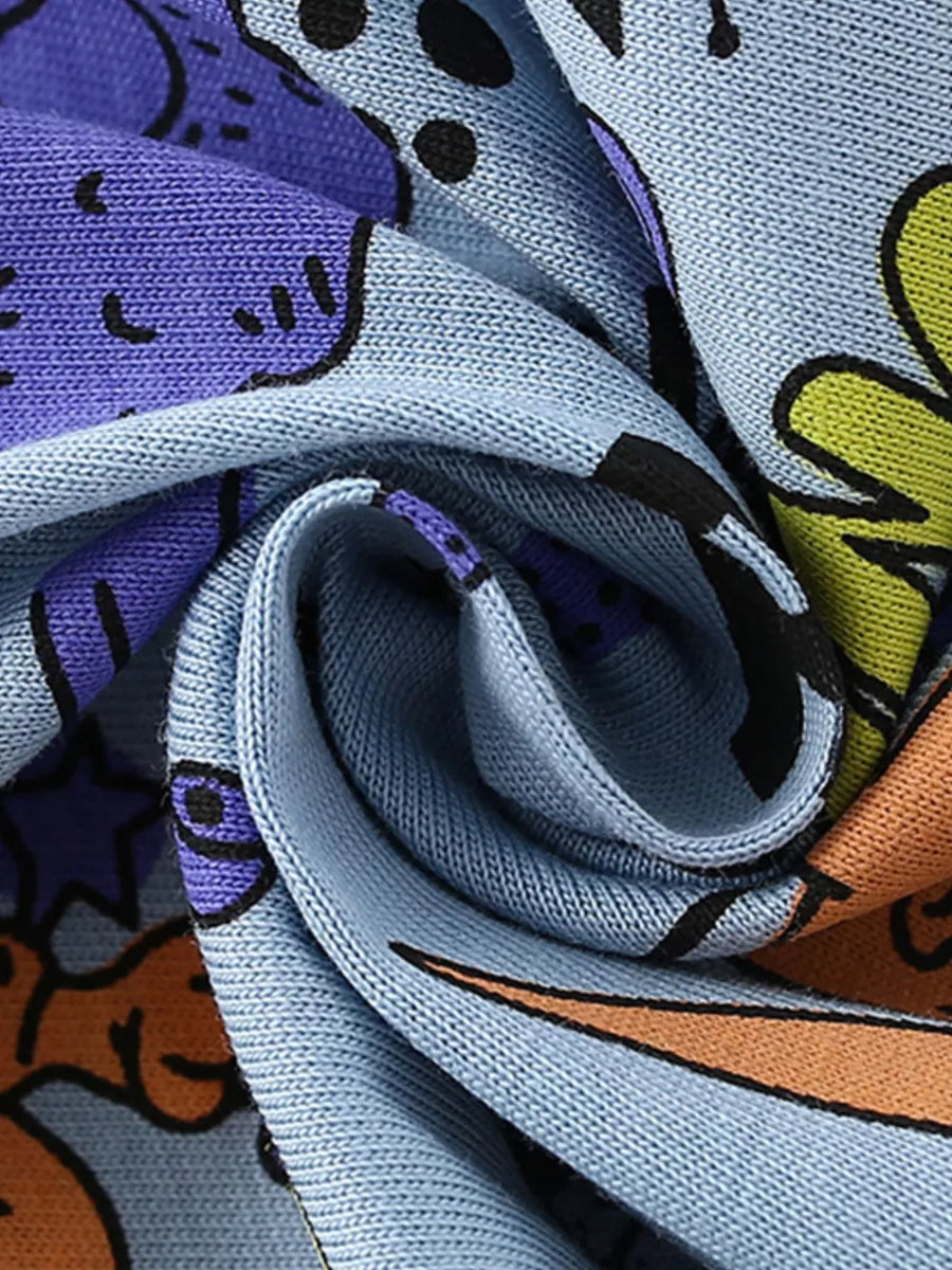 Light blue knit fabric with a playful cartoon graphic print featuring purple, orange, and yellow elements.