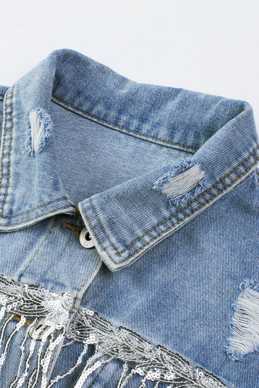 Medium wash denim trucker jacket with distressed details and sequin fringe.
