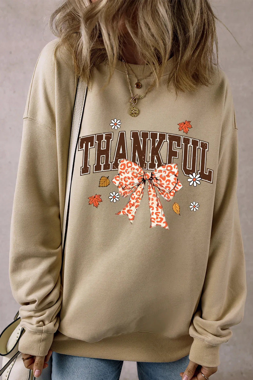 Khaki graphic sweatshirt with "THANKFUL" text and leopard print bow detail.