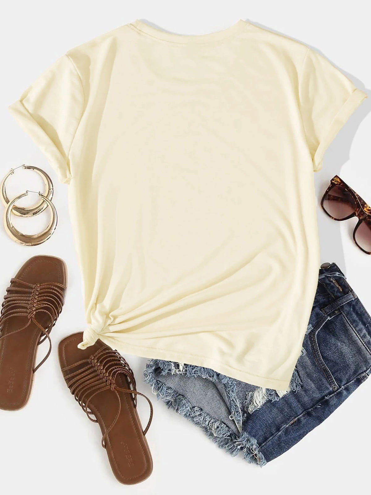 Cream t-shirt with rolled sleeves and a knotted hem, styled with denim shorts and sandals.