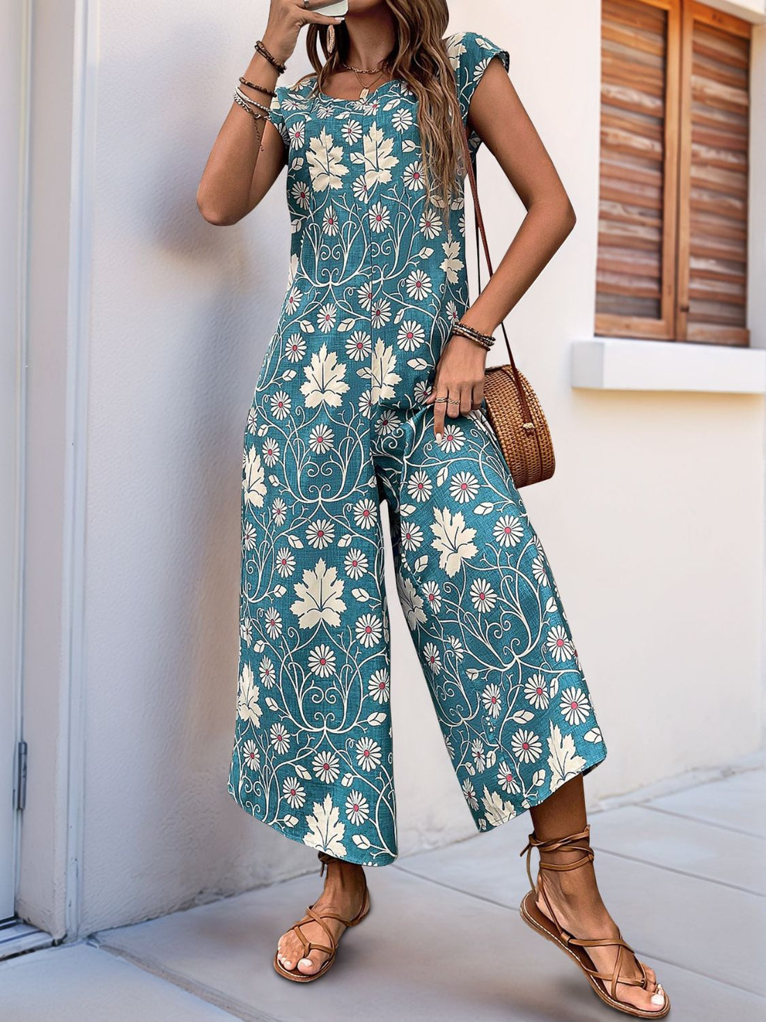 Botanical print culotte jumpsuit in turquoise with short sleeves and a round neckline.