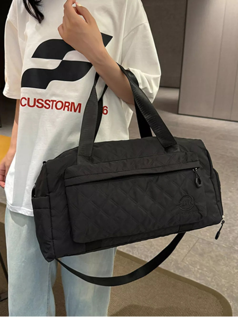 Black diamond-quilted travel bag with versatile straps and front zipper pocket.