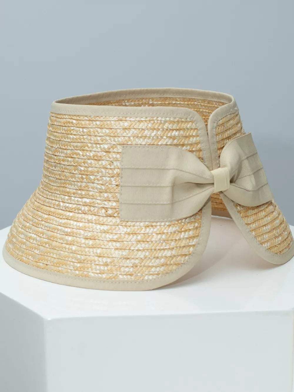 Chic straw visor hat in off-white with a decorative bow detail.