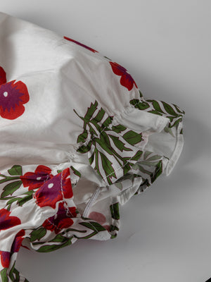 V-neck mini dress with pockets in white cotton with red floral print and ruffled sleeves.