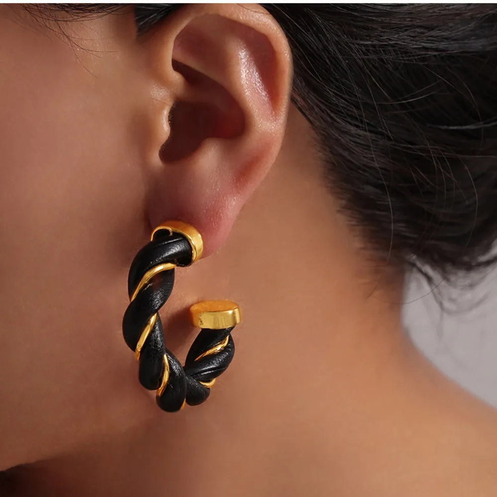 Braided black leather and gold hoop earrings with twisted detail.