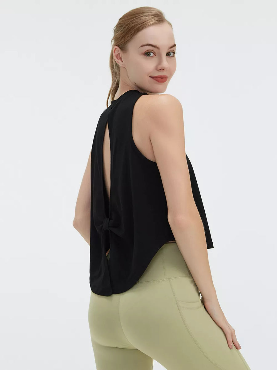Black sleeveless crop top with open back and tie detail, paired with light green leggings.