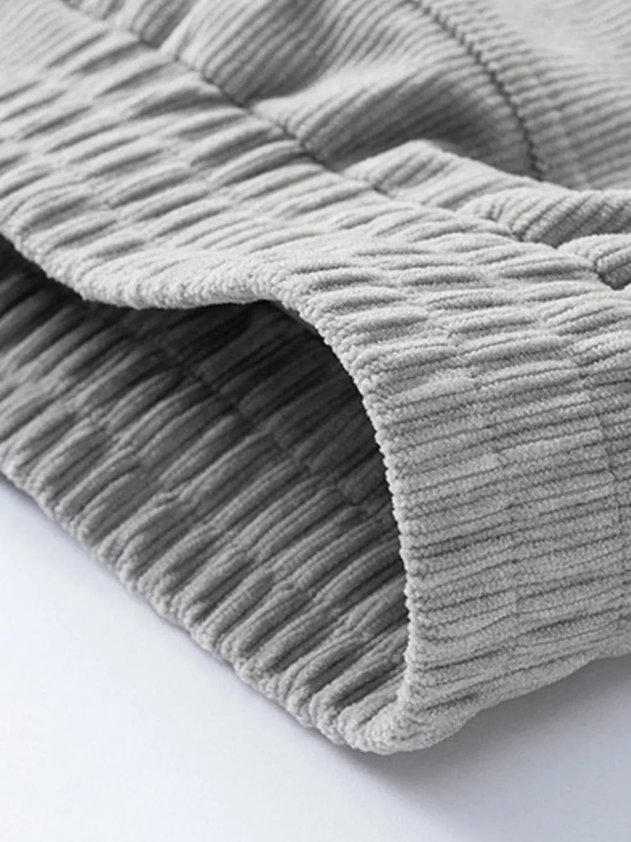 Grey corduroy trucker jacket detail showing textured fabric and seam.