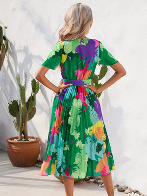 Tropical pleated midi dress in dark green with a vibrant floral print and matching belt.