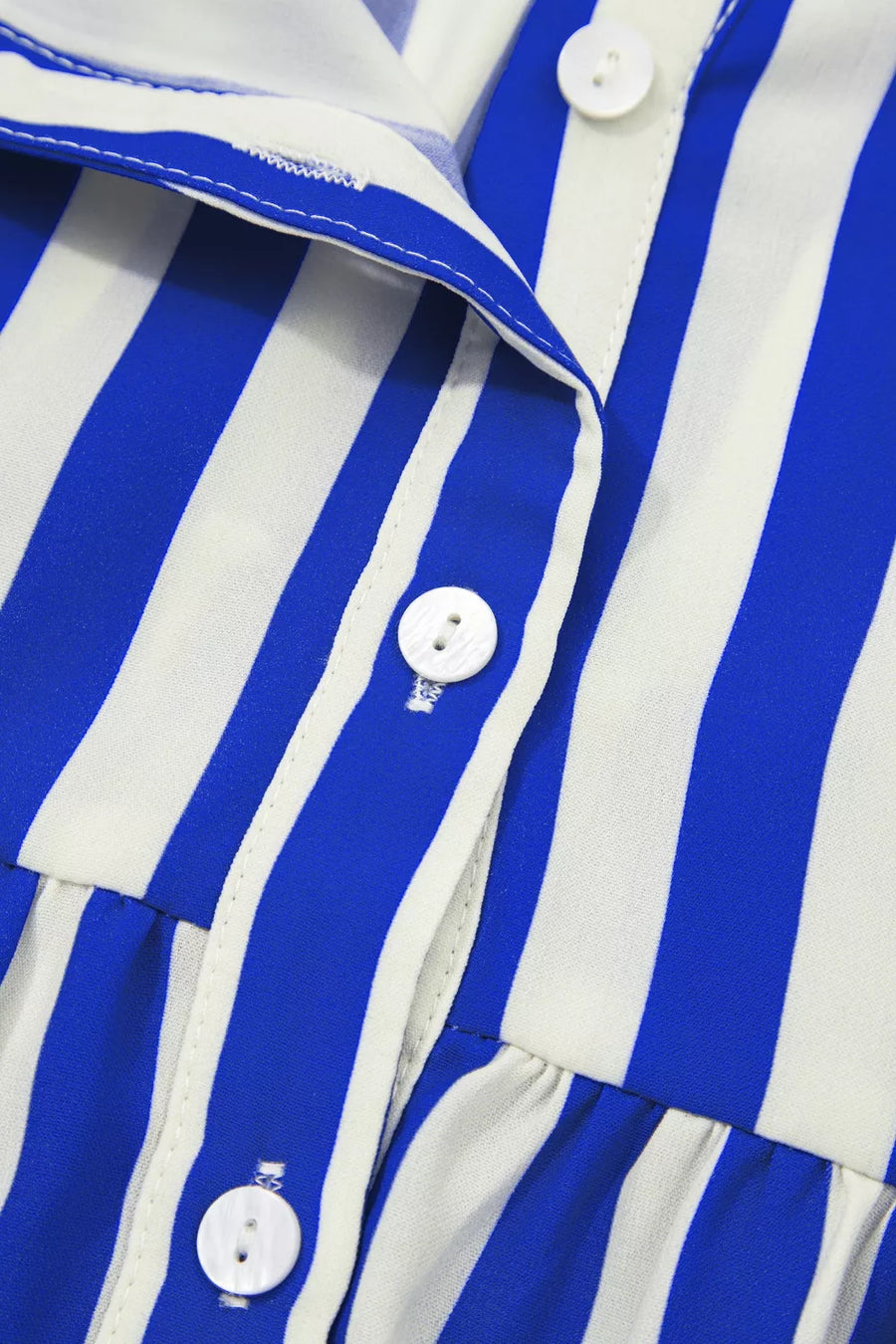 Blue and white striped button-down shirt with ruffled hem detail and white buttons.