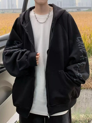 Black oversized zip-up hoodie with graphic print on sleeve, worn by a man.
