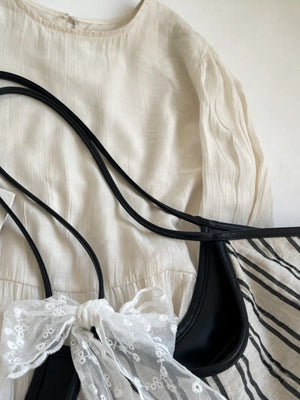 Beige shopper bag with black stripes and a white lace bow detail.