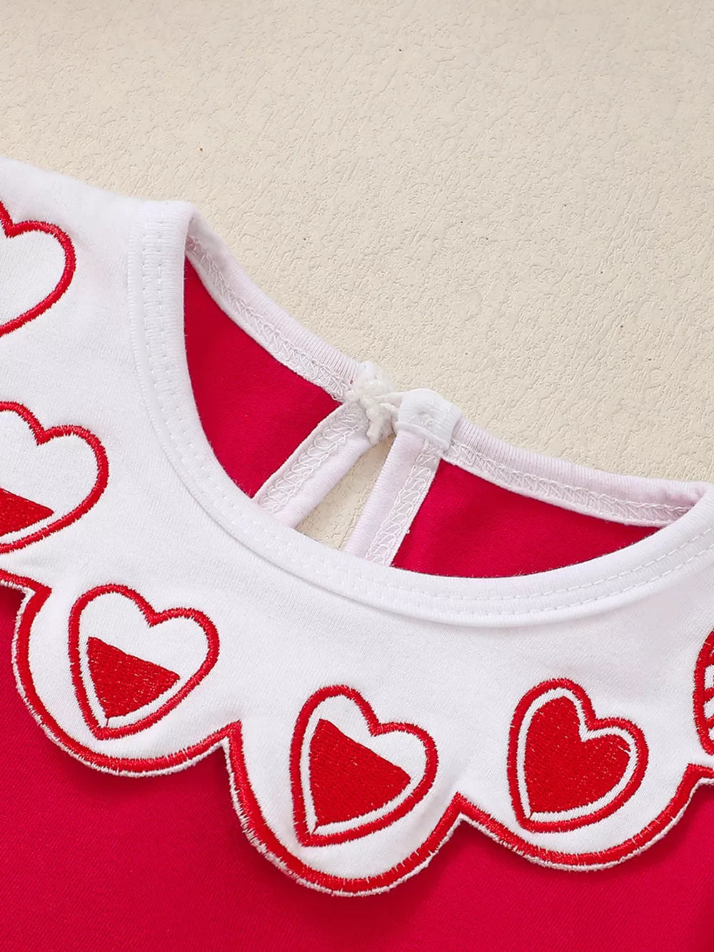Red baby dress with white scalloped collar embroidered with red hearts.