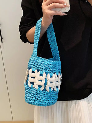 Blue woven straw bucket tote with white ring embellishments and a braided strap.
