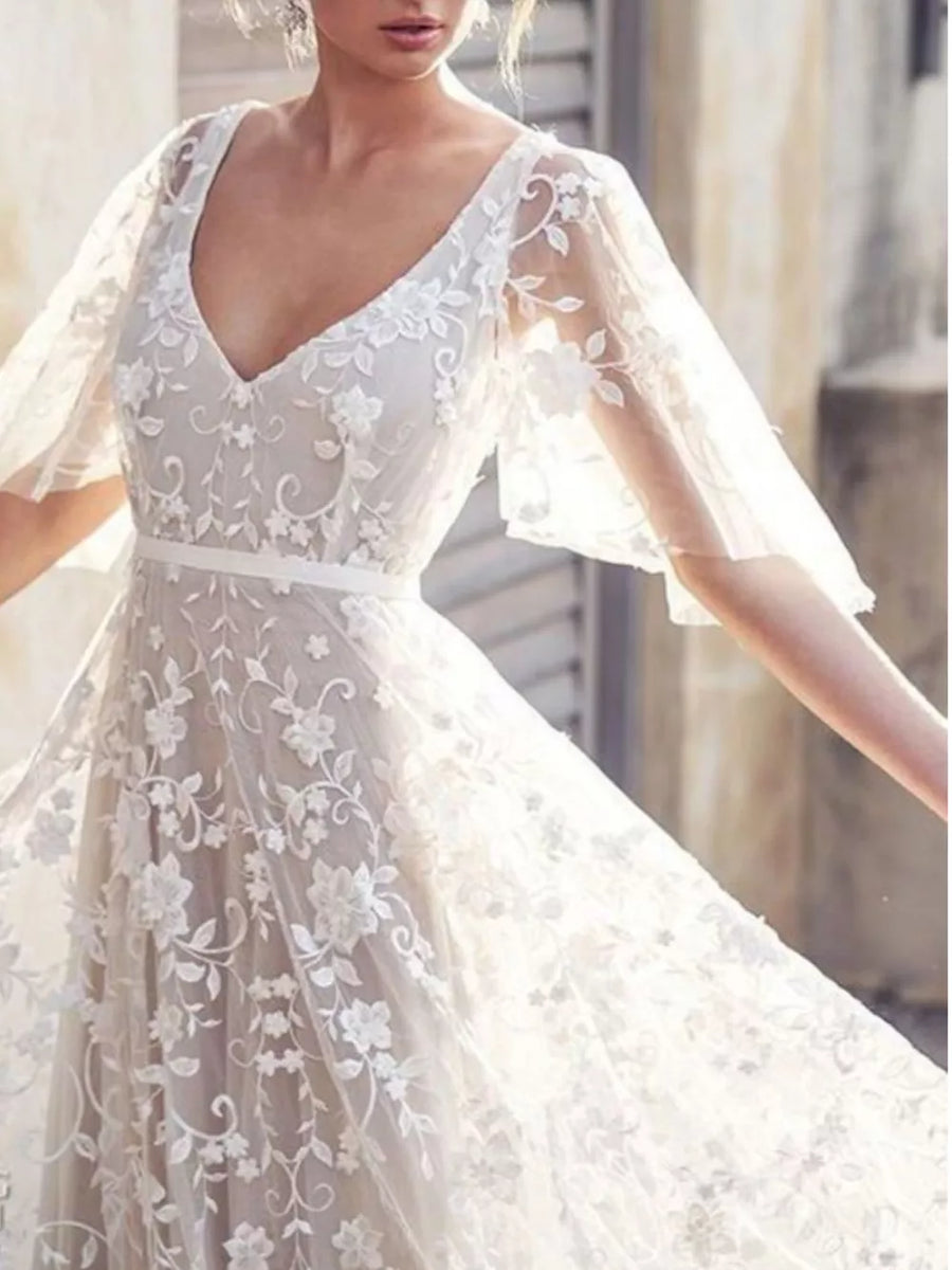 White lace flutter sleeve v-neck dress with floral embroidery and a satin sash.