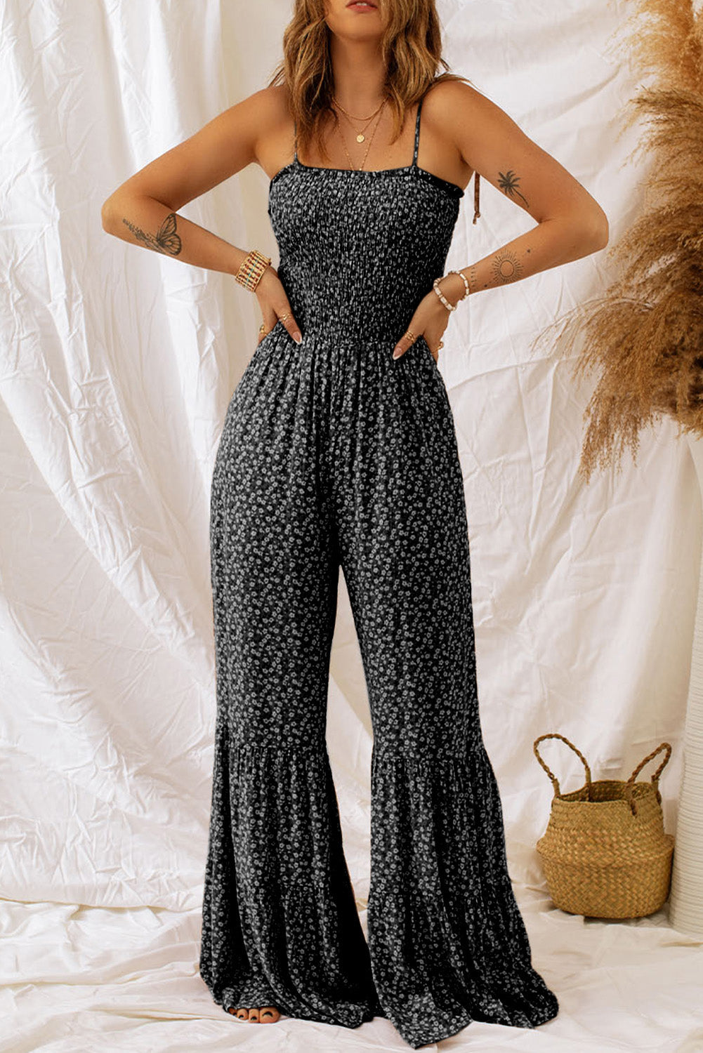 Black floral print jumpsuit with smocked bodice and flared ruffle legs.