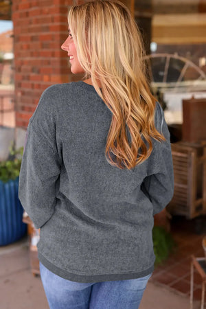 Dark gray corded sweatshirt with a relaxed fit and crew neck, styled with jeans.