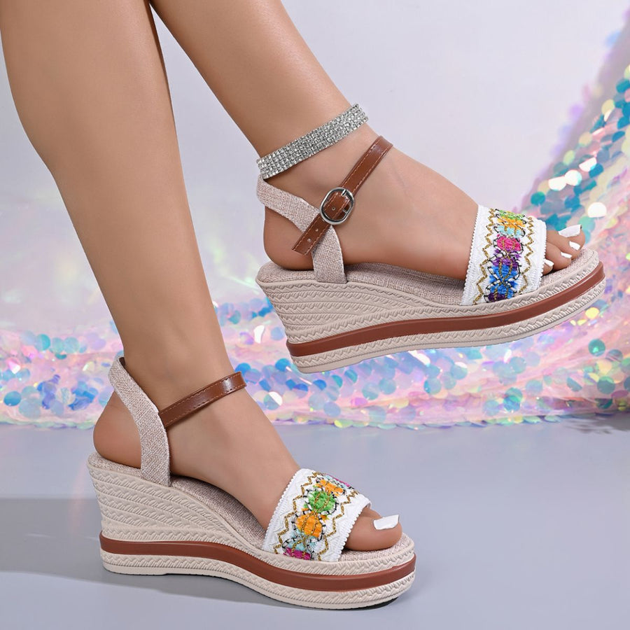 Embroidered floral wedge sandals with adjustable strap and espadrille sole.