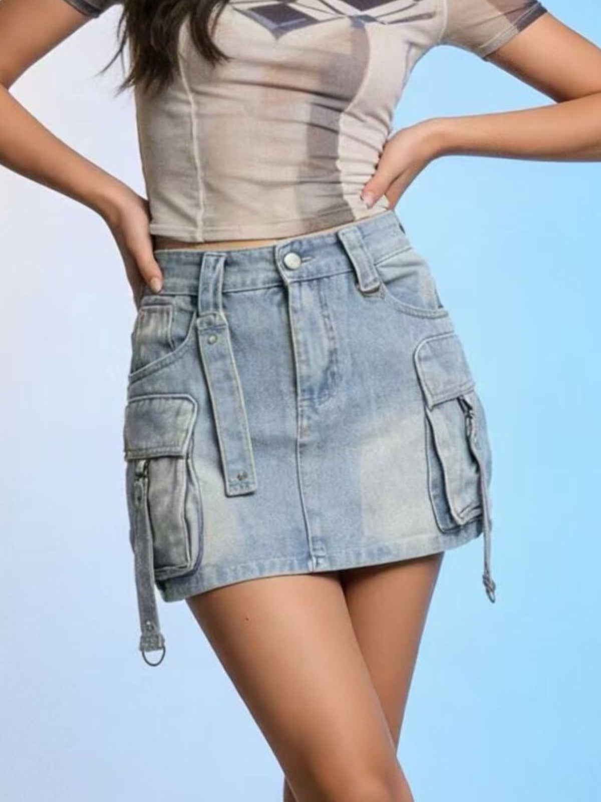 Plus size light wash denim cargo skirt with zipper pockets and buckle straps.