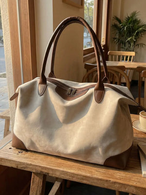 Chic slouchy travel bag in beige suede with brown leather accents and handles.