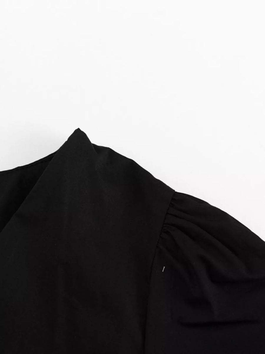 Black v-neck blouse with gathered puff sleeves and a pointed collar detail.