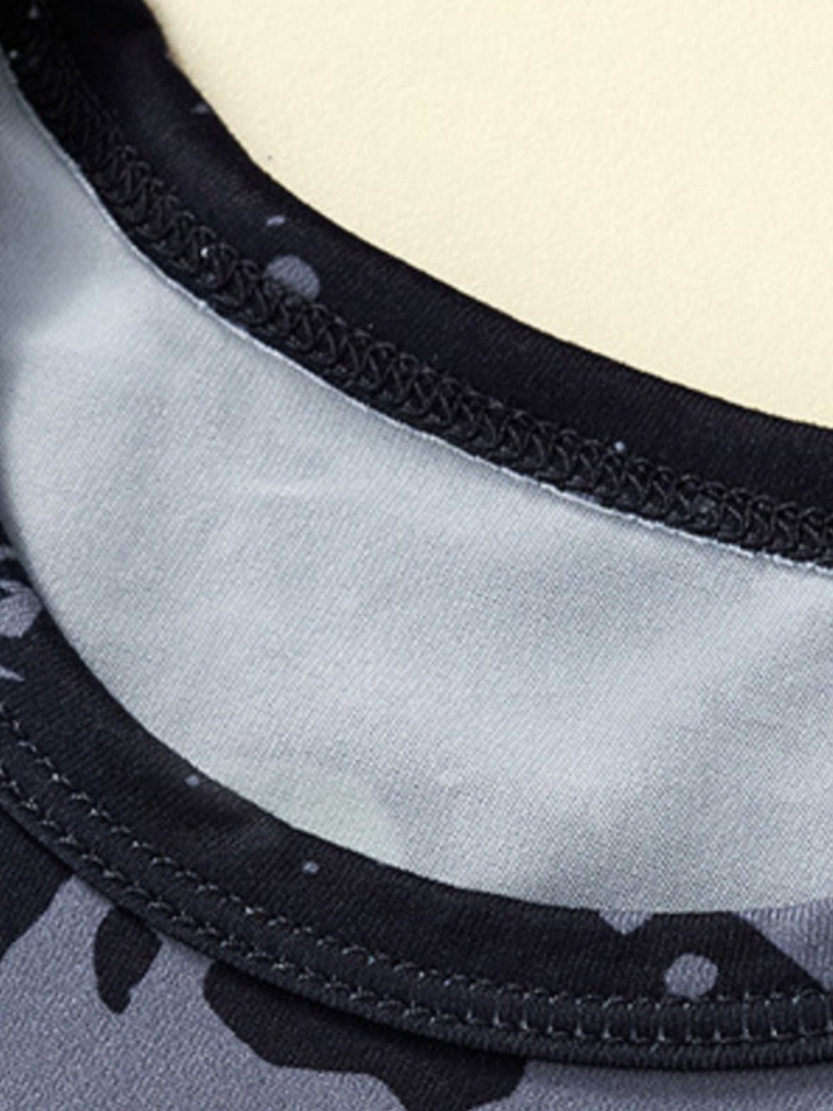 Dinosaur print toddler pajama set neckline detail with black trim and grey camouflage pattern.